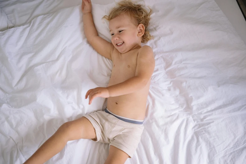 an infant boy in diapers laying on his back on the sheets