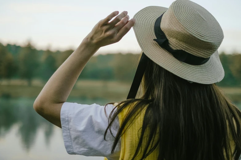 woman in sun hat standing next to the water