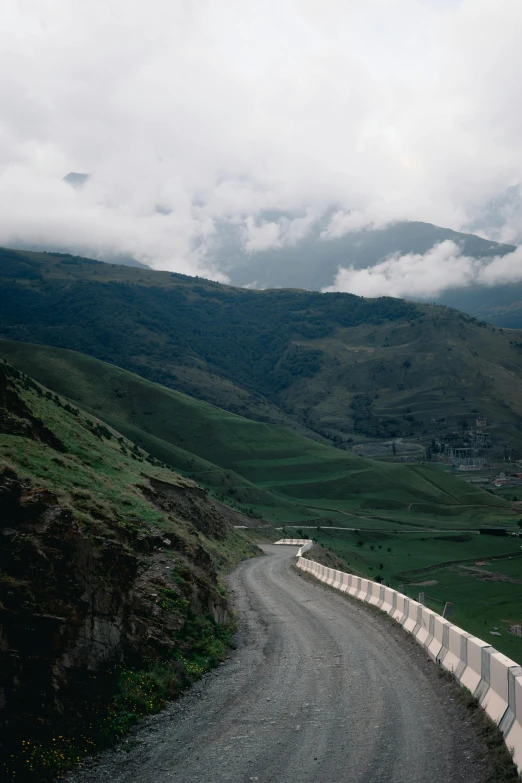 a view of an open mountain road with a bunch of clouds above