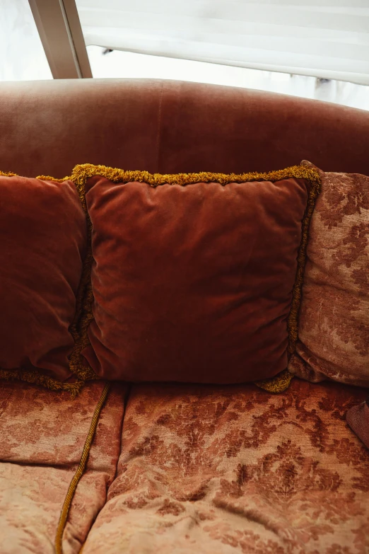 two cushions sitting on a couch in front of a window