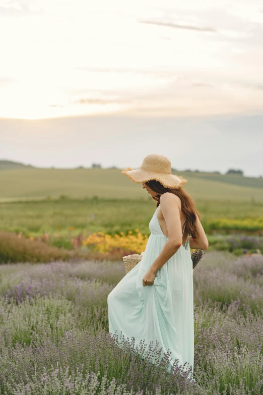 a woman standing in a lavender field at sunset