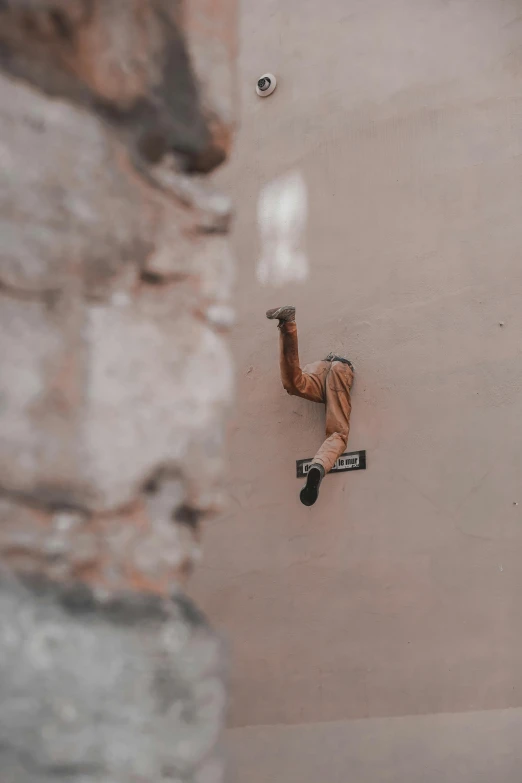 a snowboarder wearing brown clothes and black shoes is doing an upside down trick