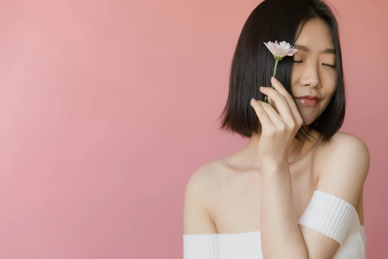 the asian woman holds a flower between her fingers