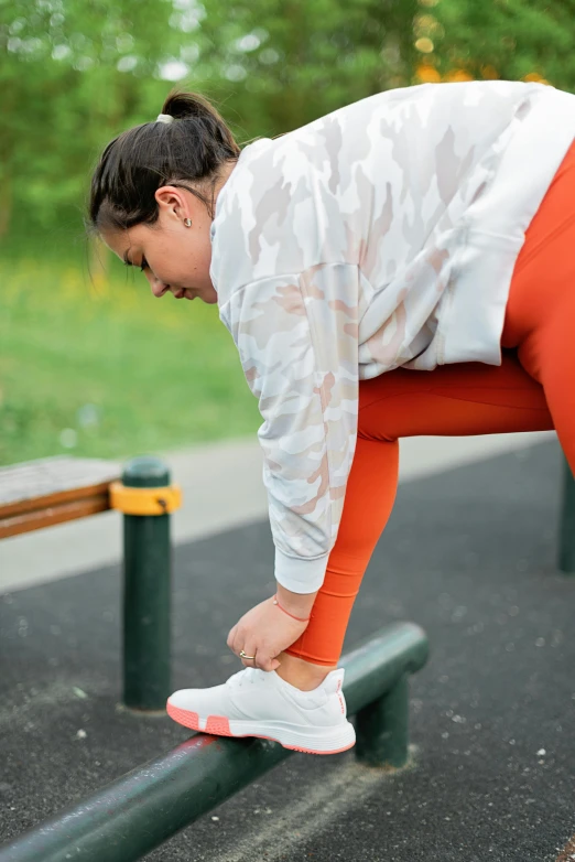 a woman putting her foot on a bench in an orange pant leggings