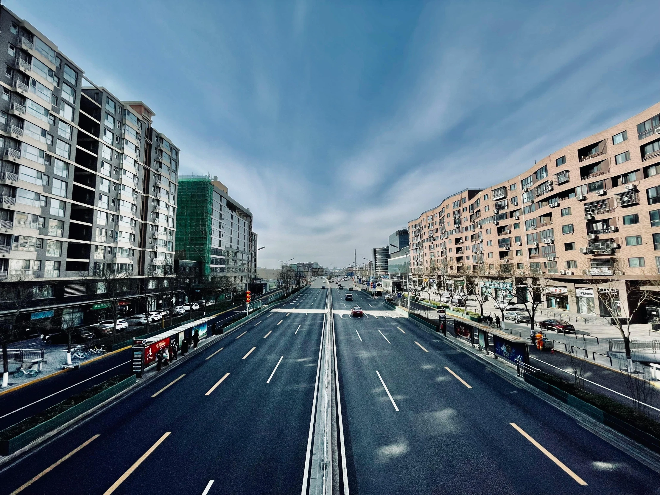 a deserted city street that has cars parked along it