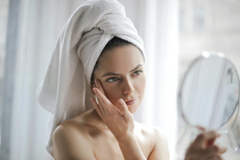 a woman wearing a towel is looking into a mirror