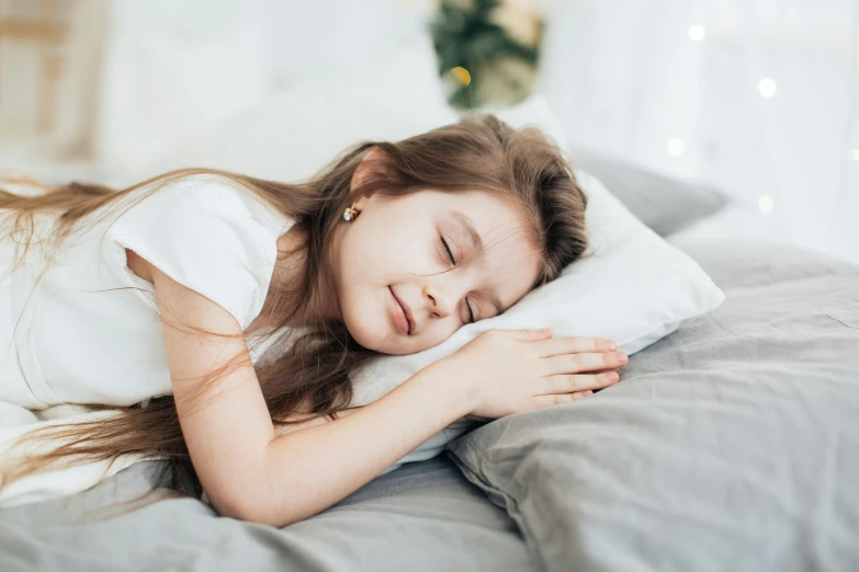 the child is asleep on a bed with a white blanket