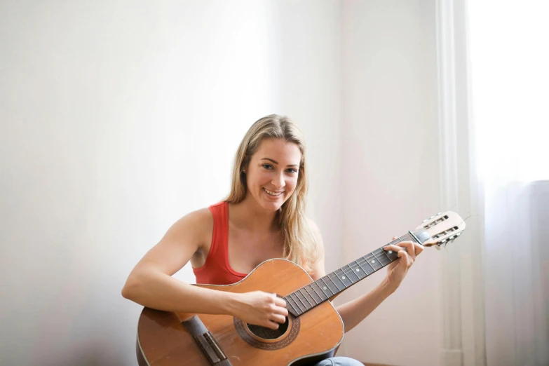 a woman sitting with an acoustic guitar and posing for the camera