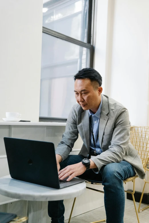 a man sitting on a stool looking at his laptop