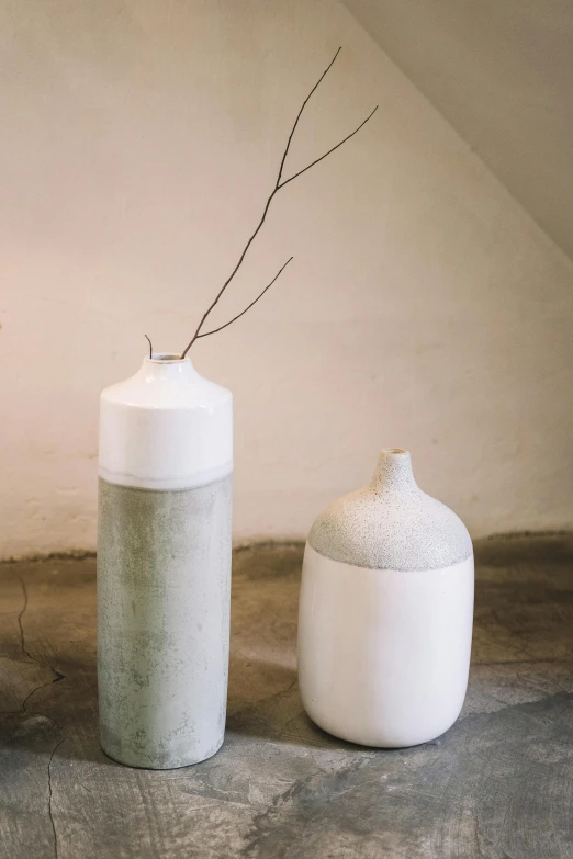 two vases one white with one gray with a nch