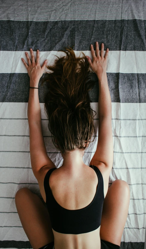 a woman in black tank top and black pants laying on top of a bed