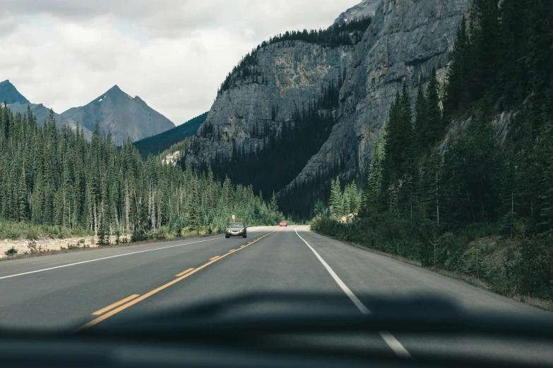 a car is driving in the middle of a mountainous region