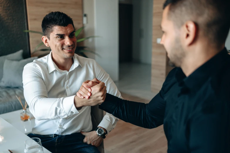 two men shaking hands, each one in white