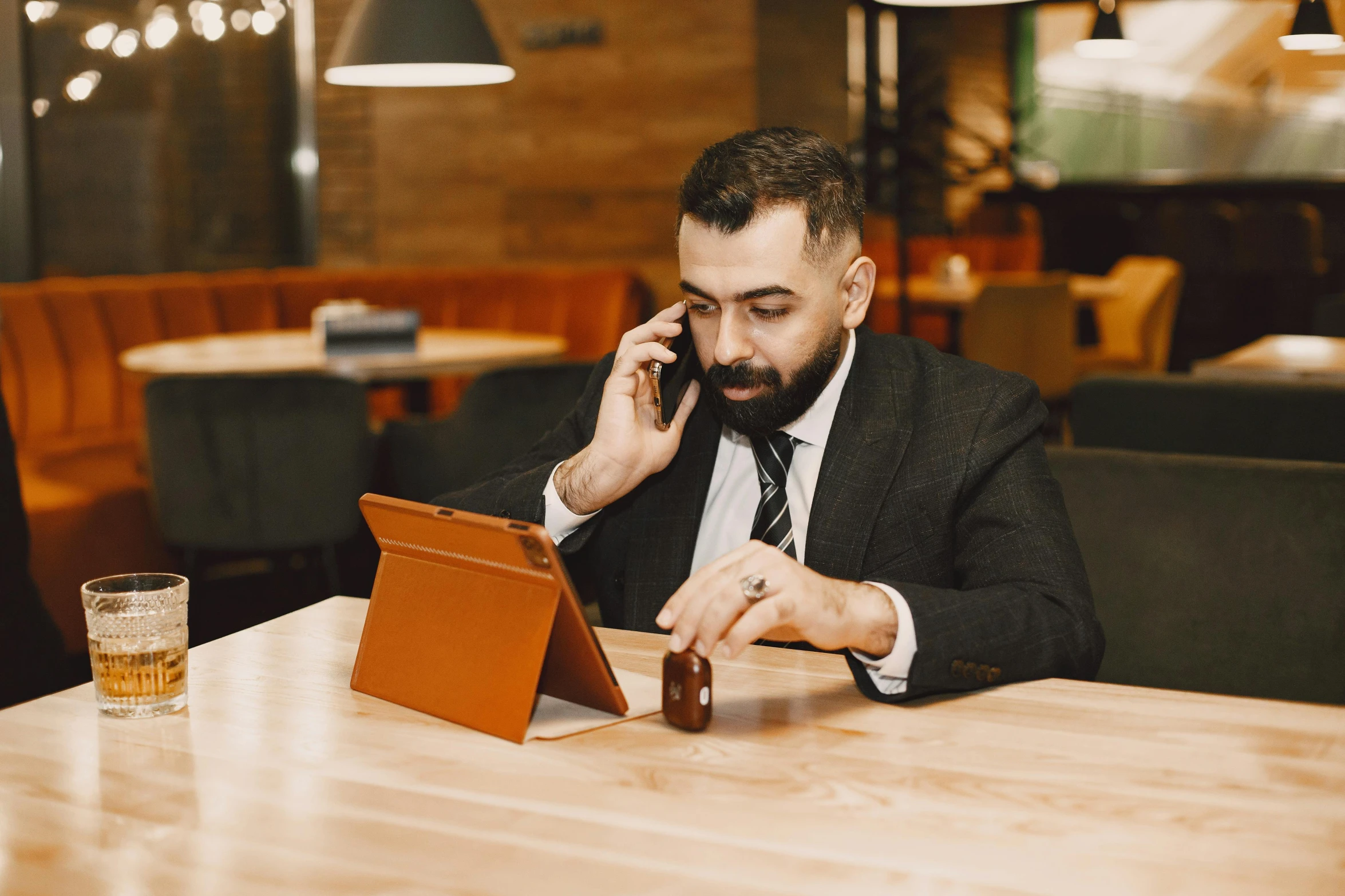 a man on a cell phone at a restaurant sitting at a table with a laptop