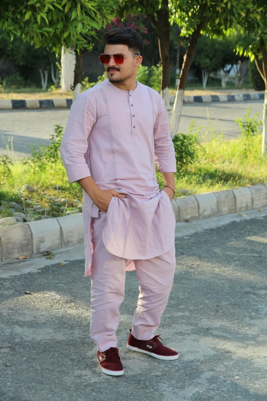 a man in pink shirt and pants standing on road