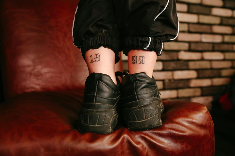 two people are tattoos on their ankles in front of a brick wall