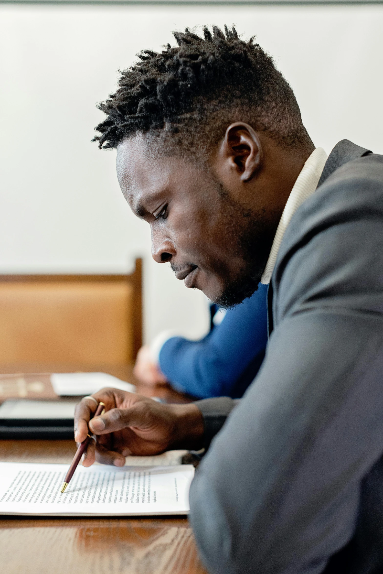 a man sitting at a desk writing with a pen and paper