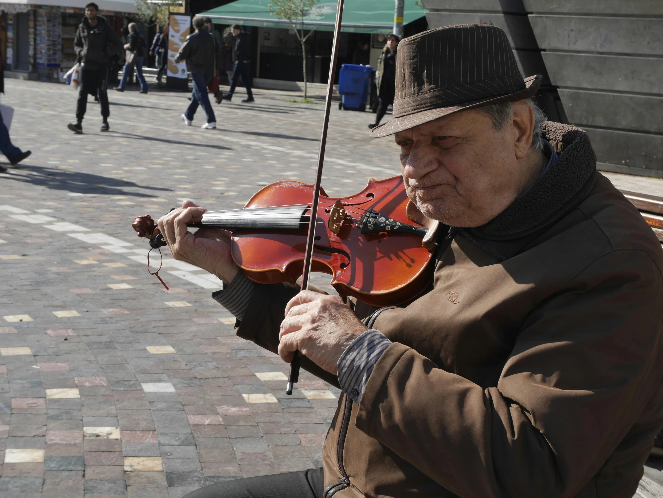 man playing violin in the middle of a city