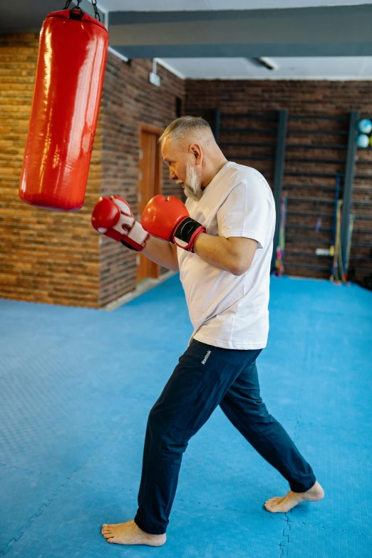 a man holding a red boxing bag next to a punching mitt