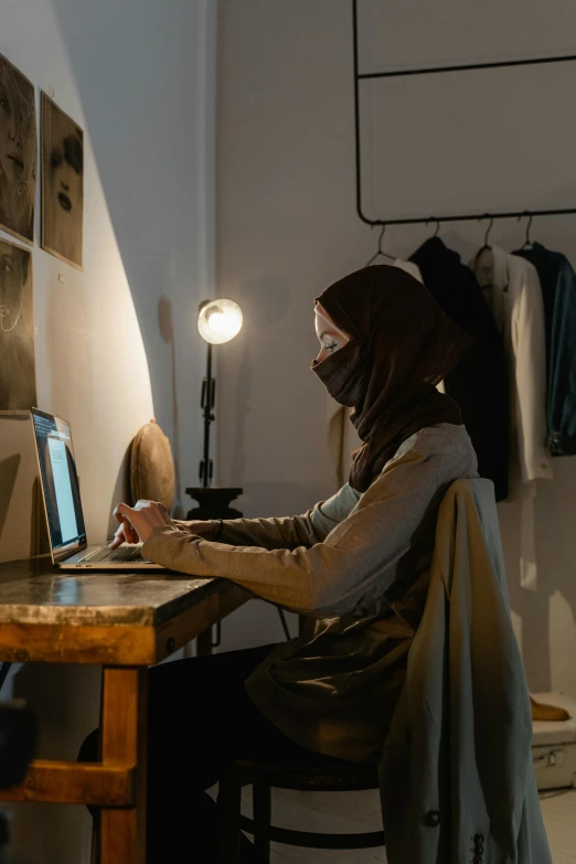 a woman using a laptop computer at a wooden desk