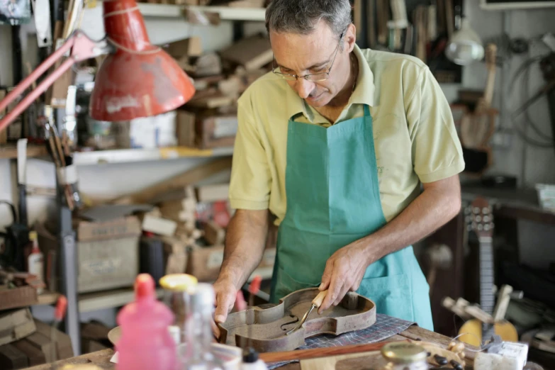 a man wearing an apron sharpes a piece of wood