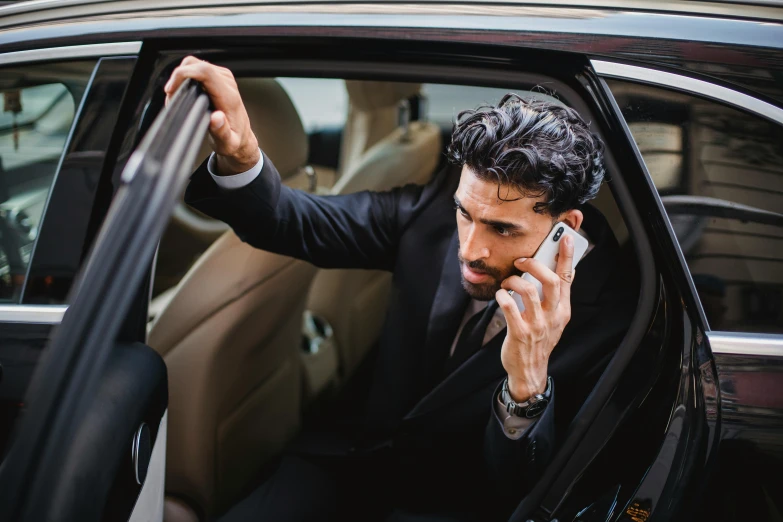 a man is sitting in a car talking on a cellphone