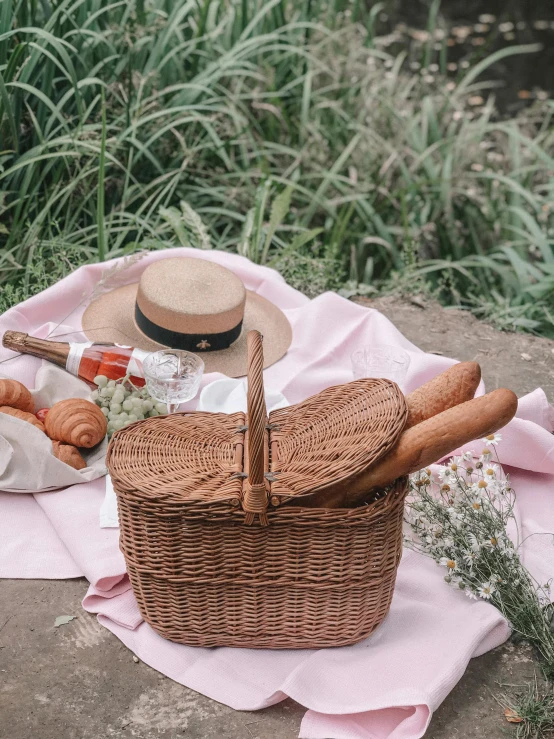 a wicker picnic basket with bread, wine and bread rolls