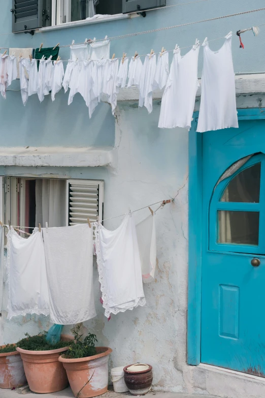 clothes hanging outside a small house with potted plants