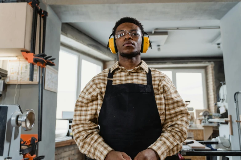 a man wearing headphones stands next to the assembly line