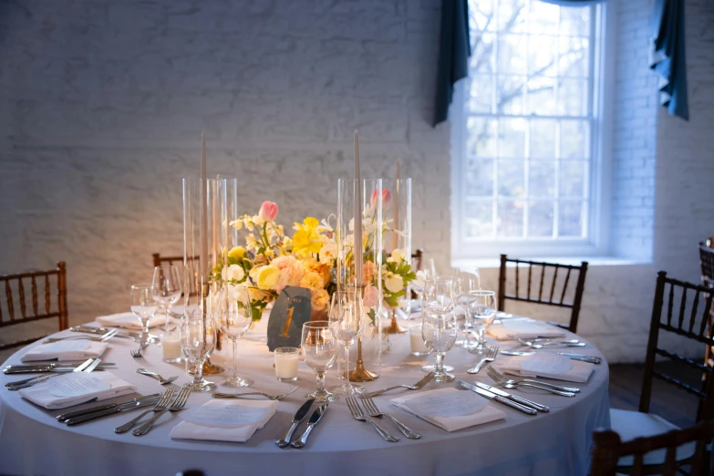 a white table is set with a vase with many flowers on it