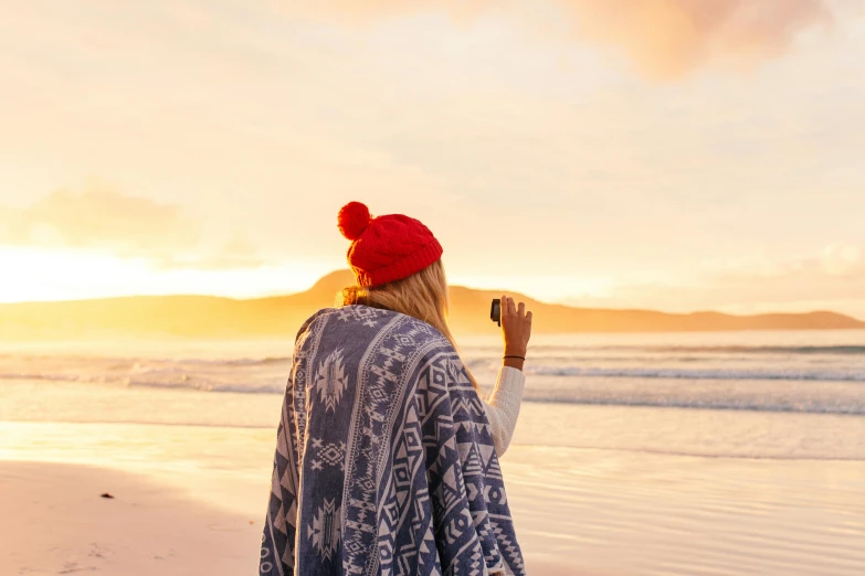 a woman is standing on a beach, looking out at the water