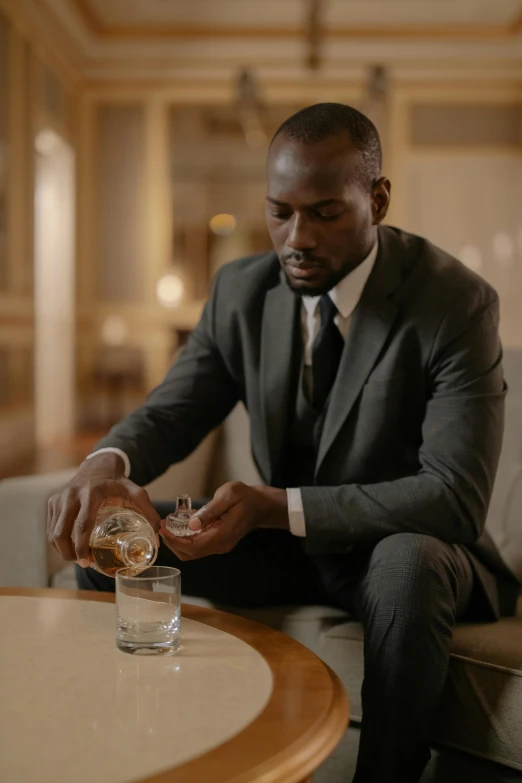 a man in a suit sitting at a table with a glass