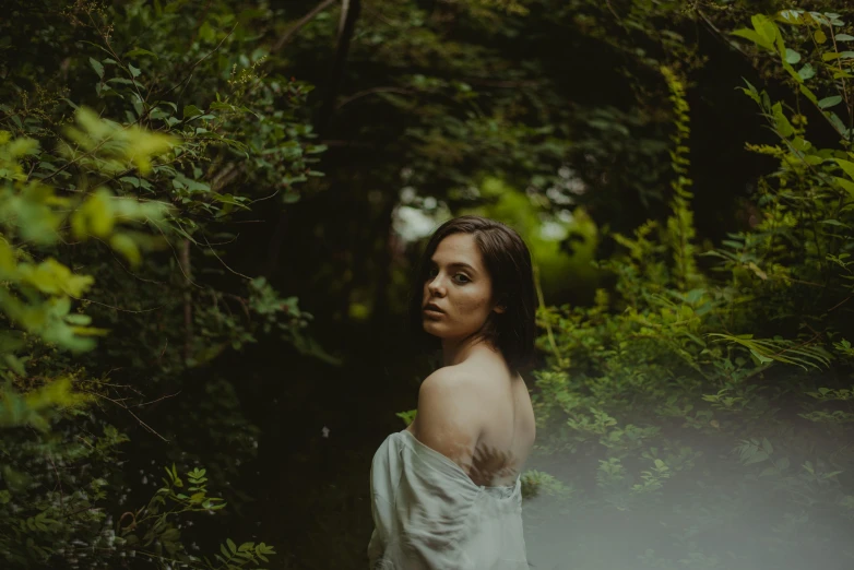 woman in white dress in front of forest