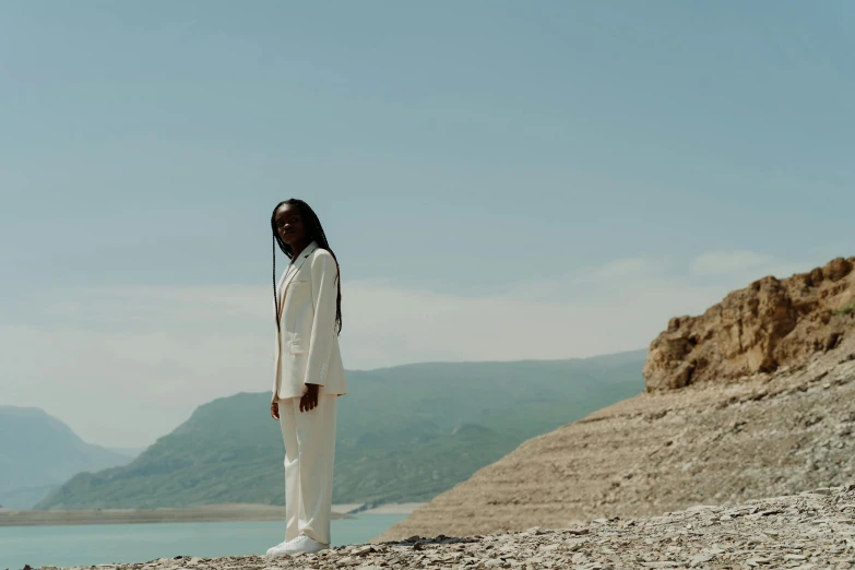 a woman wearing all white on a rocky beach