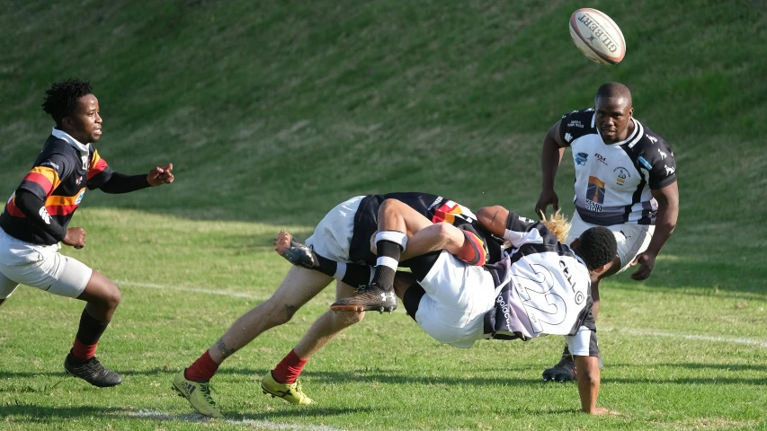 a rugby player leaps to grab the ball as others look on