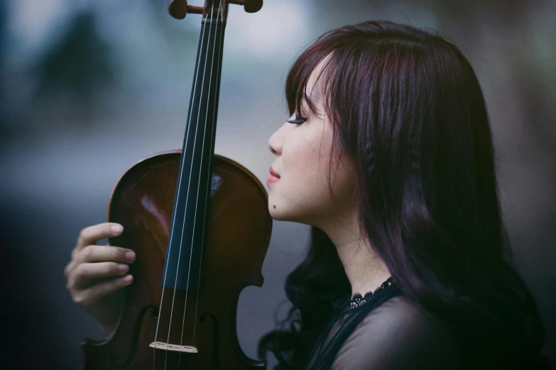 the girl holds a cello while wearing long hair