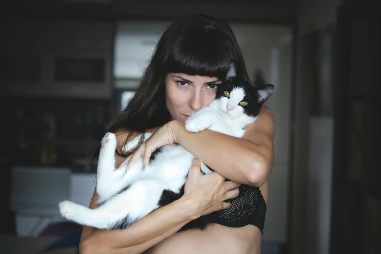 the woman is holding her cat while posing for a po