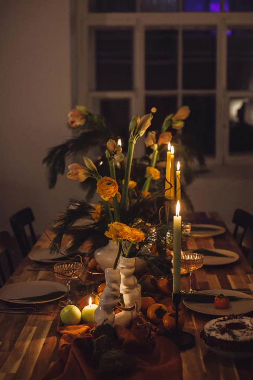 a table with two large candles, plates, and flowers on it