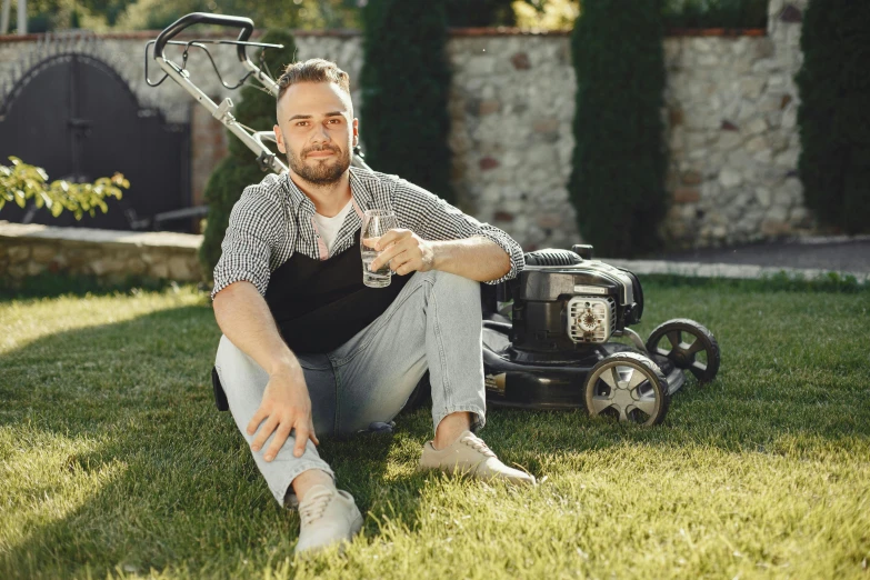 a man sitting in the grass with a garden stringing machine