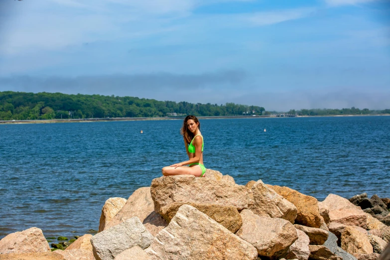 a woman sitting on a rock in the water