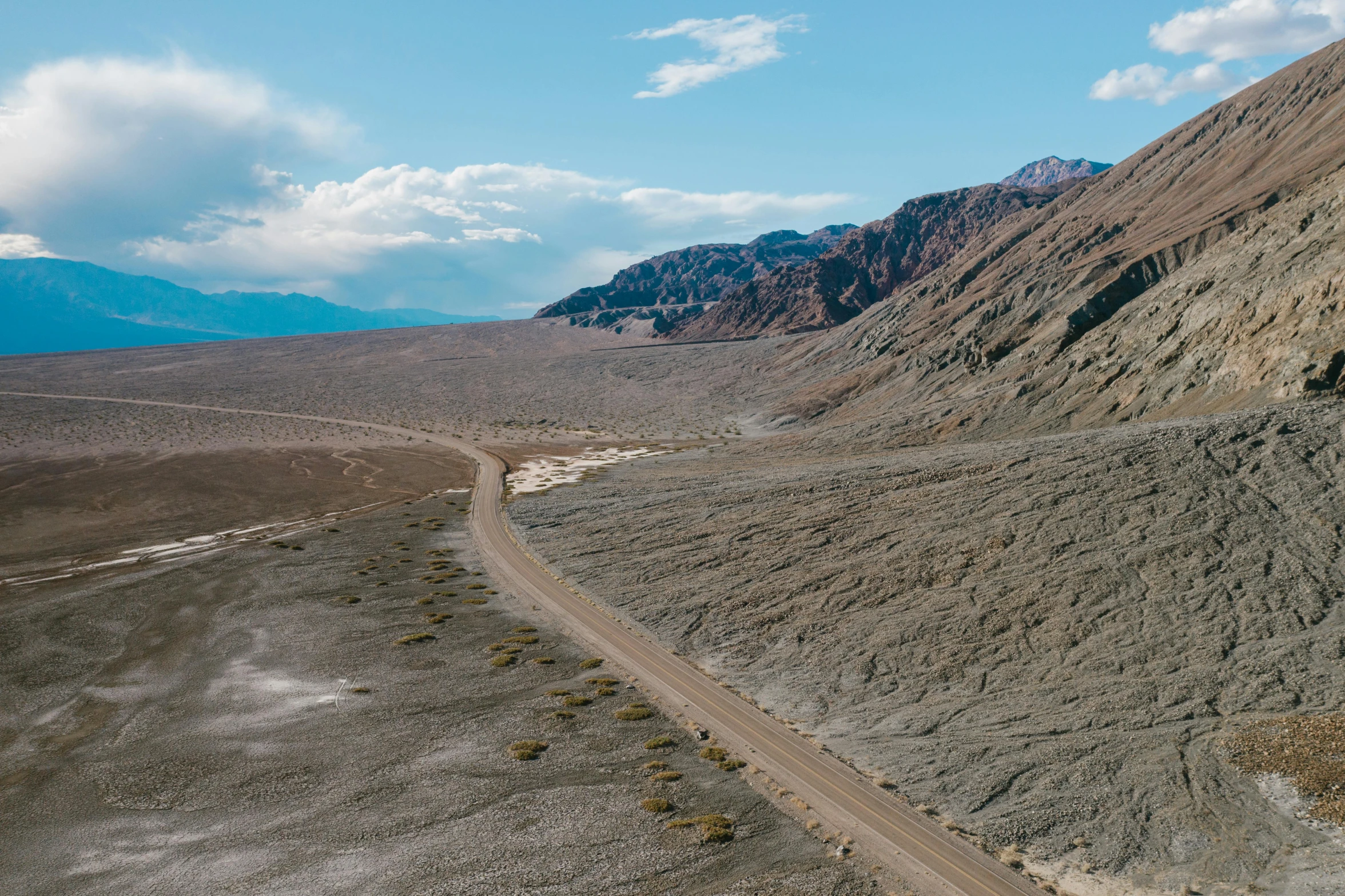 a truck driving on the side of a road through mountains