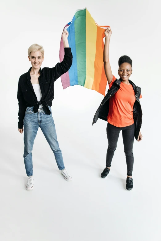 two women are holding up a rainbow kite