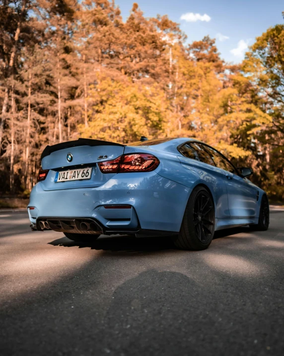 a blue bmw car sitting in front of the forest