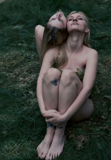 two  females laying in the grass on their backs