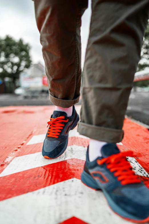 the feet of a man standing on a red and white stripe on the street