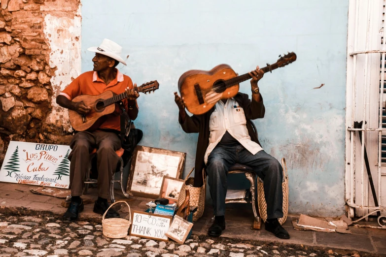 two people sitting on the curb with guitars