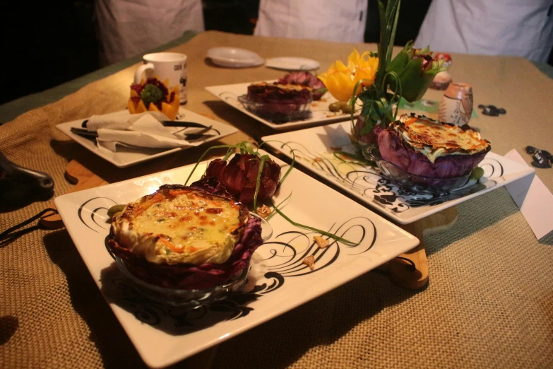 a dining table that has three plates with various types of food