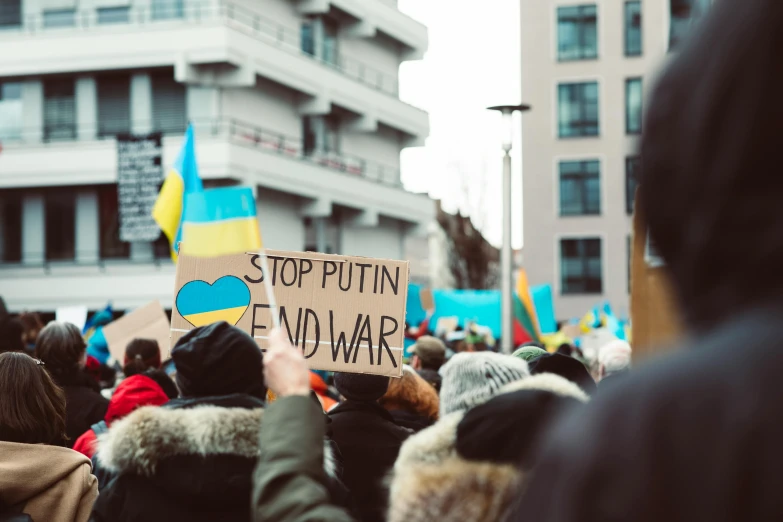 many people are holding signs with blue, green, yellow, and blue designs on them