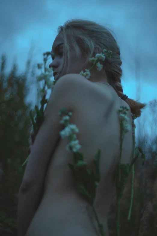 woman with long hair and flowers on her shoulders is in grass