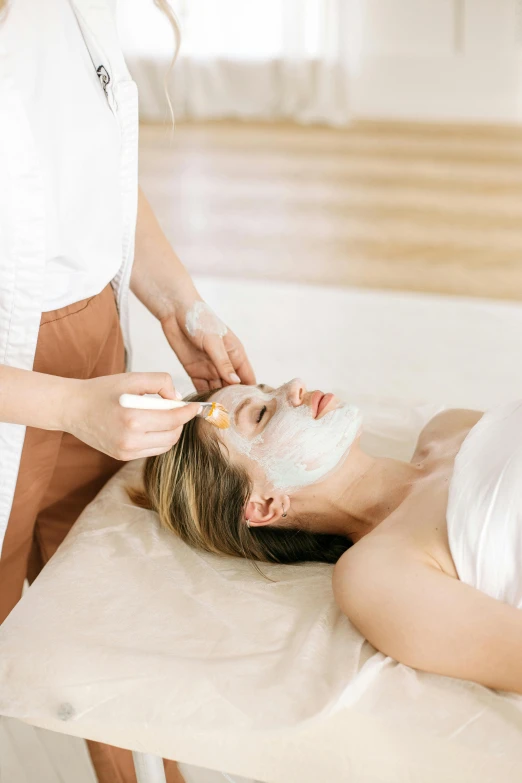 the woman is getting her facial mask done with the help of the master